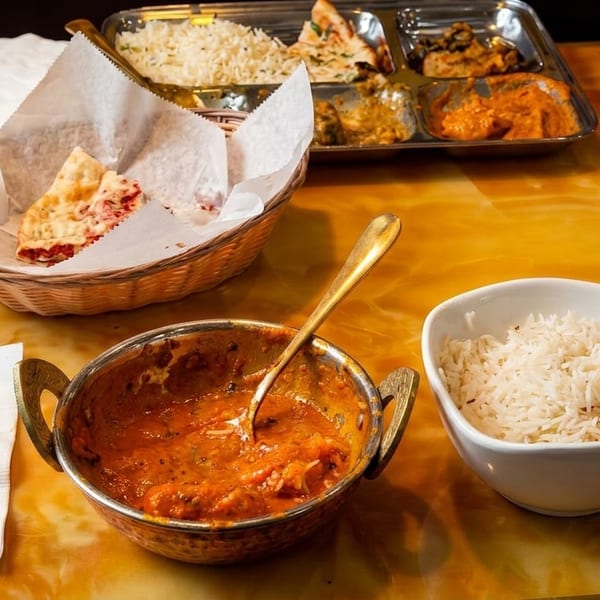 Indian food on a table, including naan, rice, curry, and a thali platter.