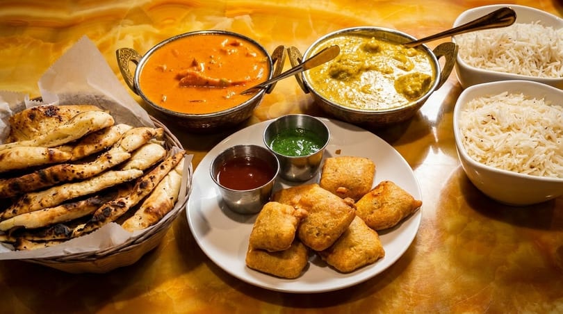 Indian feast with chicken tikka masala, saag paneer, rice, naan, pakoras, and chutneys.